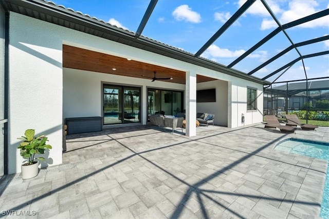 back of property featuring a patio, glass enclosure, ceiling fan, an outdoor hangout area, and stucco siding