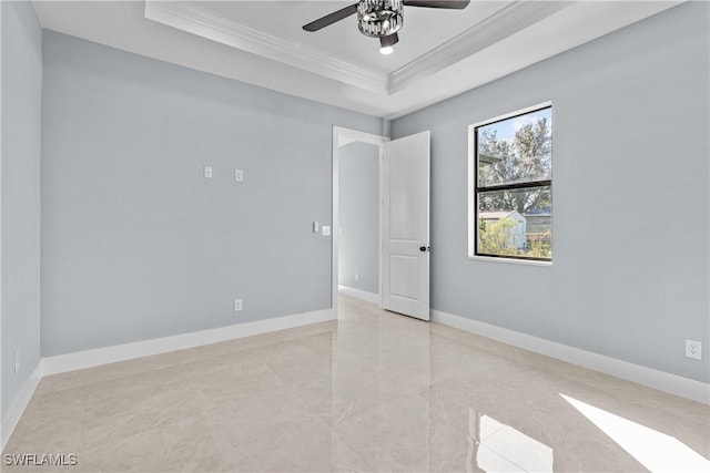 empty room with crown molding, a tray ceiling, and ceiling fan