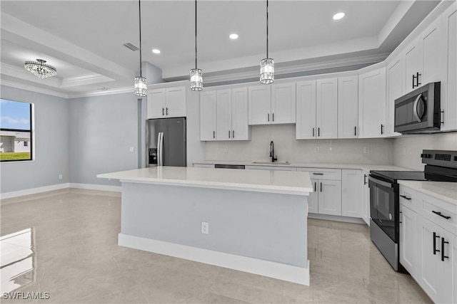 kitchen with stainless steel appliances, white cabinetry, a kitchen island, and a tray ceiling