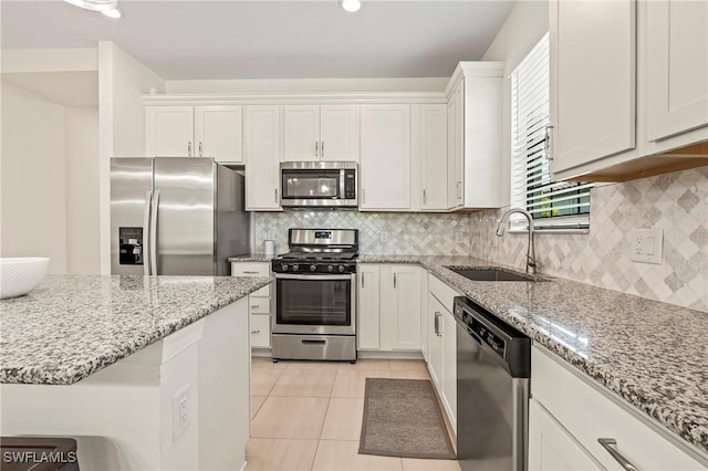 kitchen with sink, white cabinets, light tile patterned floors, light stone counters, and stainless steel appliances