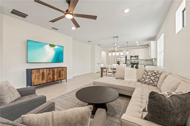 living room with sink, light tile patterned floors, and ceiling fan