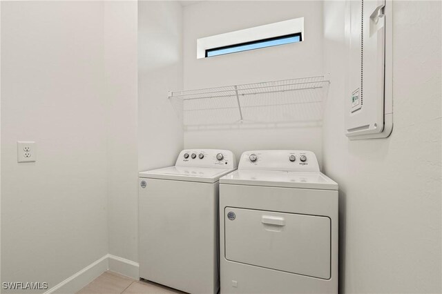 laundry area with washing machine and clothes dryer and light tile patterned flooring