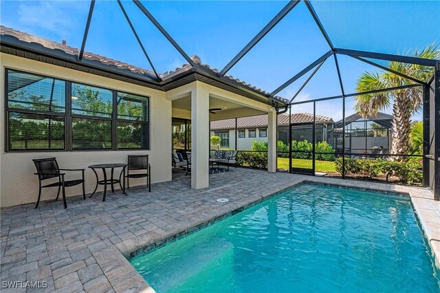 view of swimming pool with a patio, a lanai, and ceiling fan