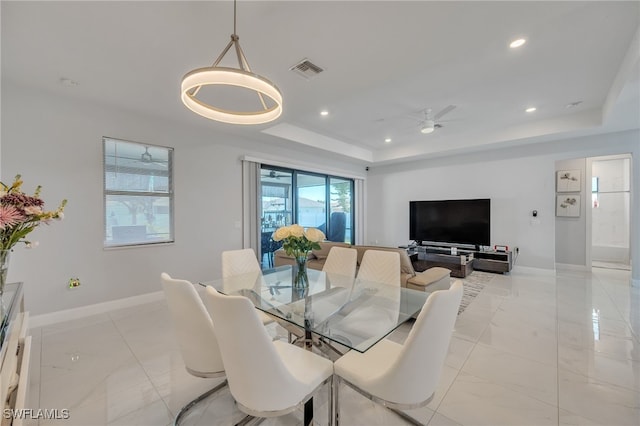 dining space with ceiling fan and a raised ceiling