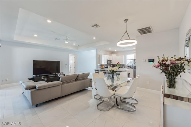 living room with ceiling fan and a tray ceiling