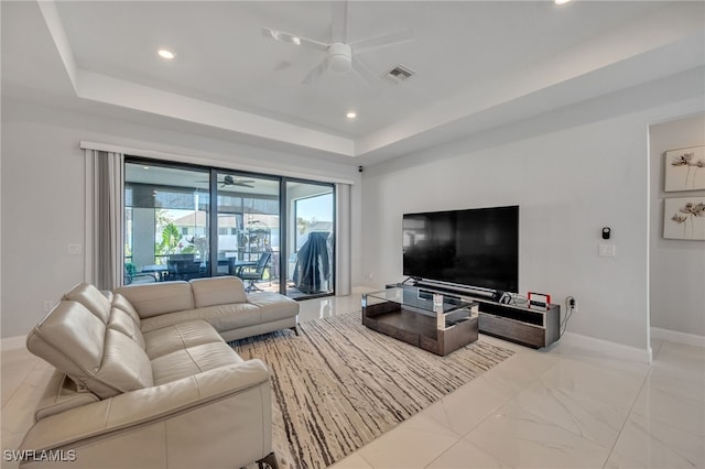 living room with ceiling fan and a tray ceiling