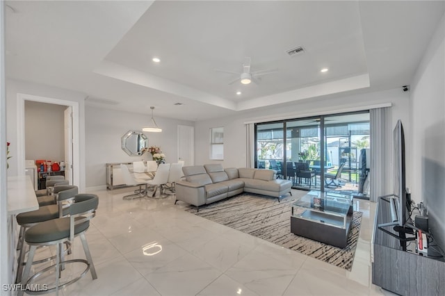 living room with ceiling fan and a raised ceiling