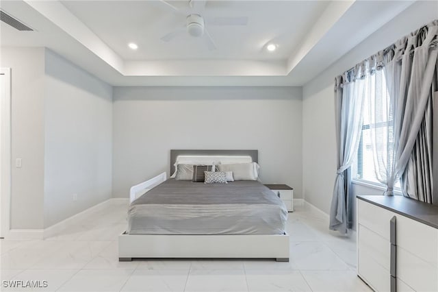 bedroom featuring multiple windows, a raised ceiling, and ceiling fan