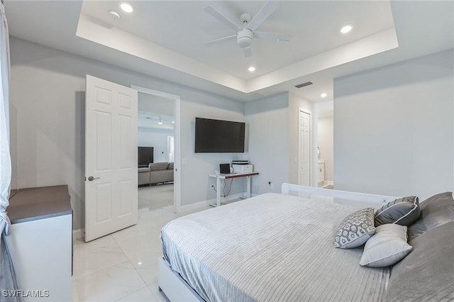 bedroom with connected bathroom, a tray ceiling, a closet, and ceiling fan