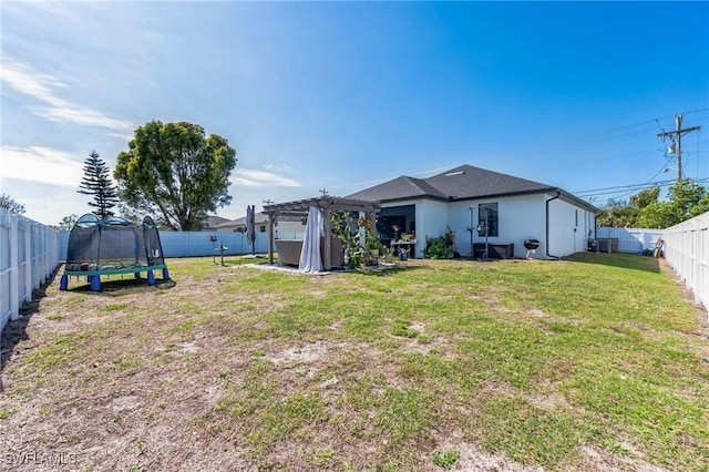 rear view of house featuring a yard, central AC, a trampoline, and a pergola