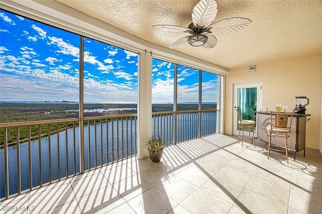 unfurnished sunroom featuring a water view and ceiling fan