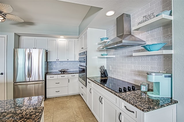 kitchen featuring dark stone countertops, white cabinets, stainless steel fridge, and ventilation hood