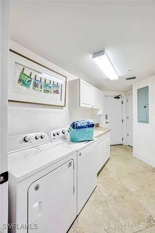 clothes washing area featuring cabinets, washer and dryer, and electric panel