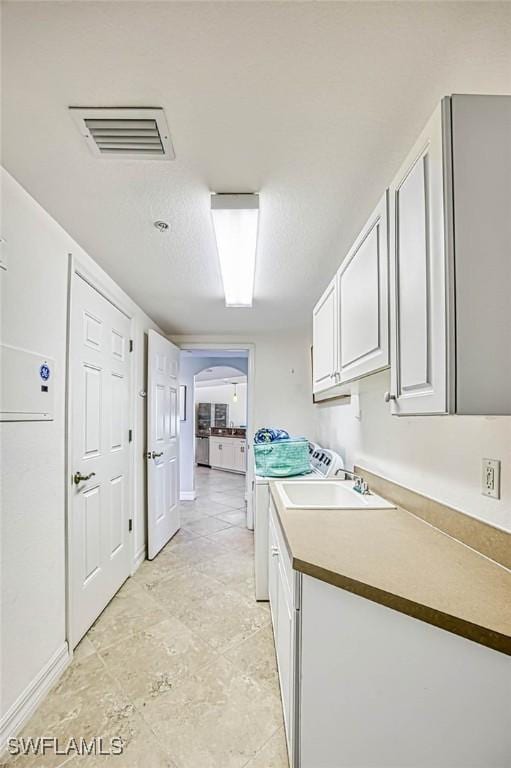 clothes washing area with cabinets, sink, and washing machine and clothes dryer