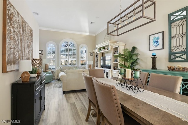 dining area with crown molding and light wood-type flooring