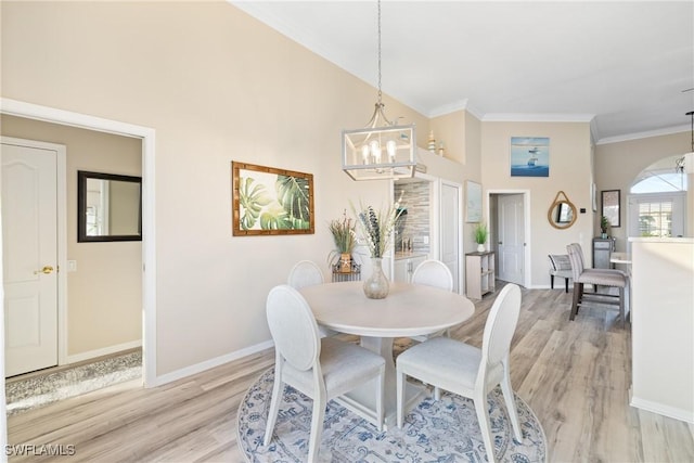 dining area with a notable chandelier, light hardwood / wood-style flooring, ornamental molding, and a high ceiling