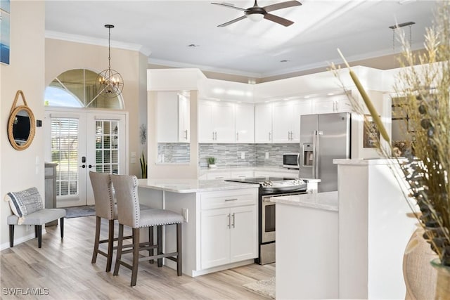 kitchen featuring white cabinetry, decorative light fixtures, light stone countertops, and appliances with stainless steel finishes