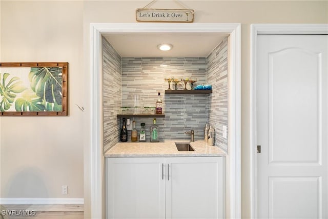 bar featuring sink, backsplash, and white cabinets