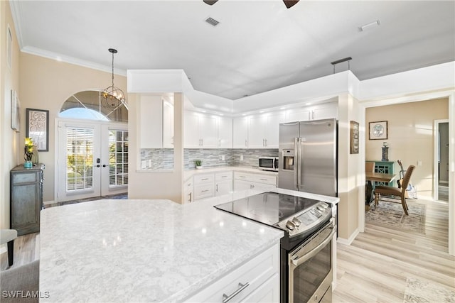 kitchen featuring pendant lighting, appliances with stainless steel finishes, backsplash, white cabinets, and french doors