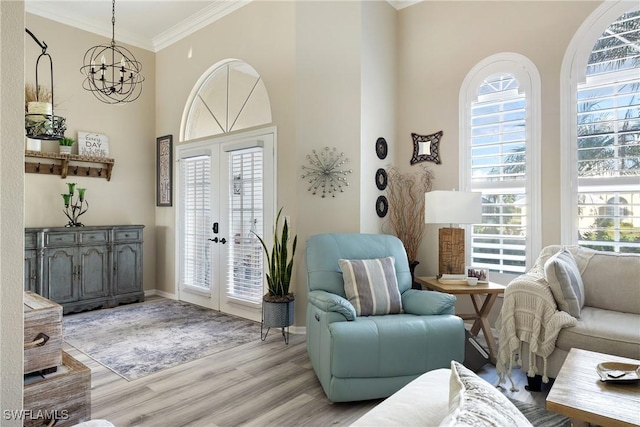 foyer with french doors, ornamental molding, a chandelier, and light hardwood / wood-style floors