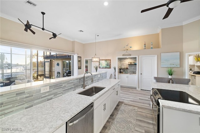 kitchen featuring sink, light hardwood / wood-style flooring, appliances with stainless steel finishes, hanging light fixtures, and white cabinets