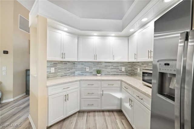 kitchen with light stone counters, stainless steel appliances, white cabinets, and light wood-type flooring