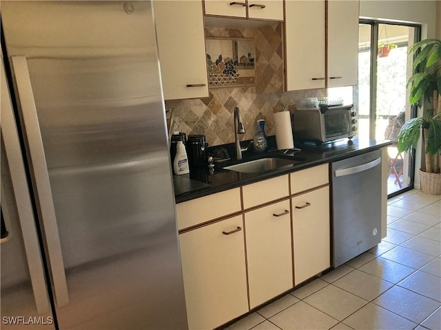 kitchen with sink, white cabinetry, backsplash, stainless steel appliances, and light tile patterned flooring