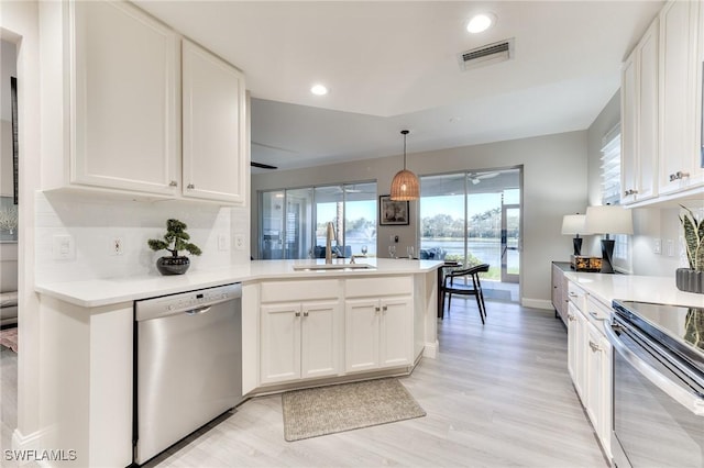 kitchen with sink, appliances with stainless steel finishes, light hardwood / wood-style floors, white cabinets, and decorative light fixtures