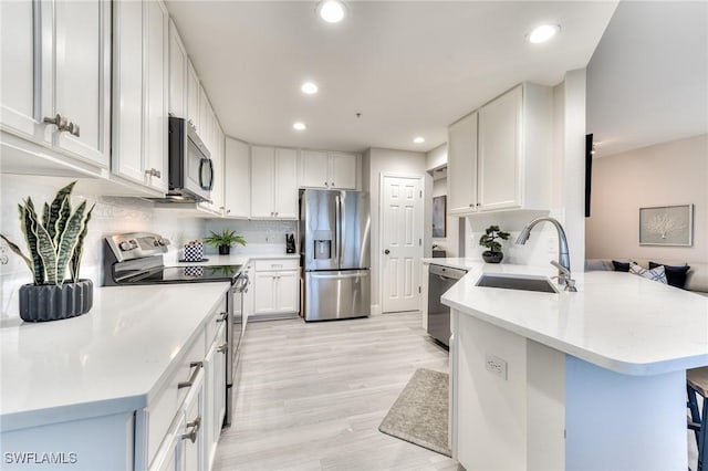 kitchen with white cabinetry, sink, a kitchen bar, and appliances with stainless steel finishes