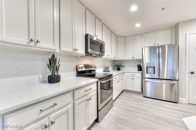 kitchen with backsplash, stainless steel appliances, light hardwood / wood-style floors, and white cabinets