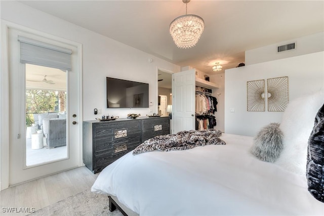 bedroom featuring access to outside, light hardwood / wood-style floors, and a chandelier