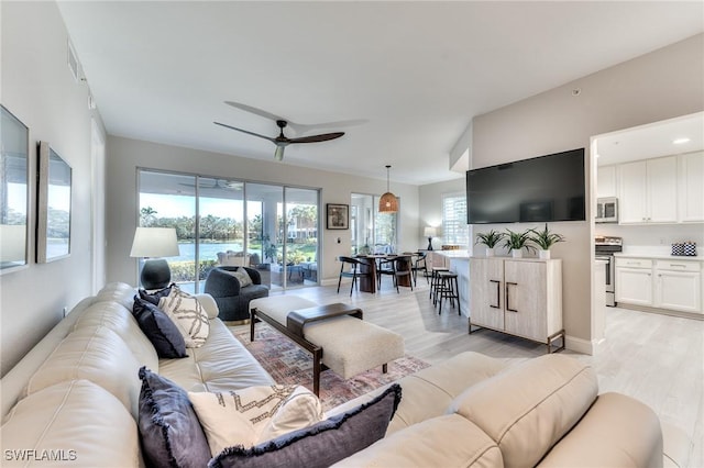 living room with plenty of natural light, ceiling fan, and light hardwood / wood-style flooring