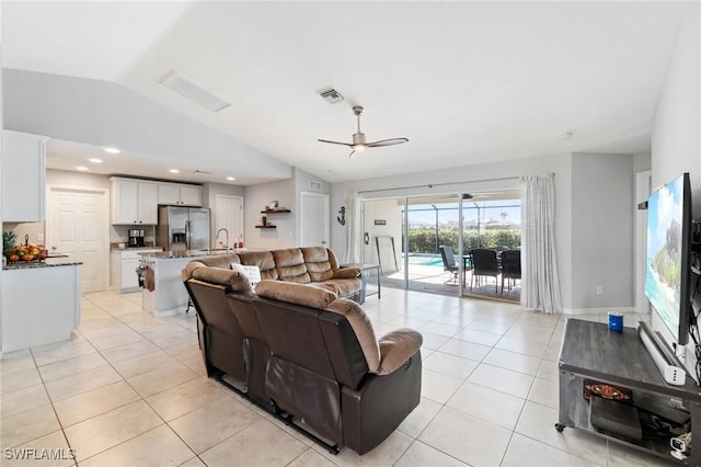 living room featuring vaulted ceiling, sink, light tile patterned floors, and ceiling fan