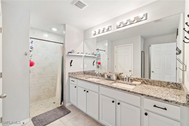 bathroom with tiled shower, vanity, and tile patterned floors