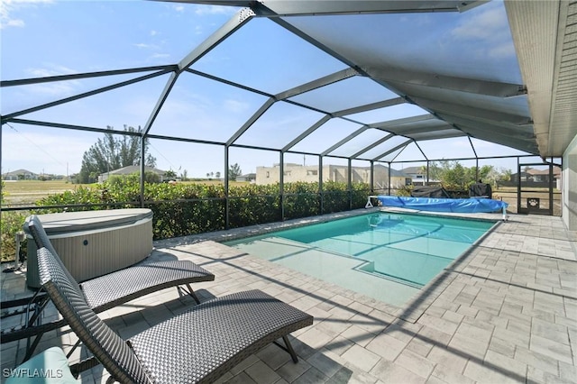 view of swimming pool featuring a hot tub, a patio, and glass enclosure