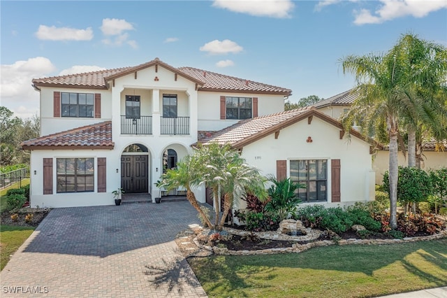 mediterranean / spanish house with a balcony and a front lawn