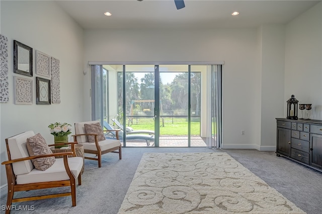 living area with light carpet and ceiling fan