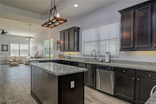 kitchen featuring sink, light stone counters, decorative light fixtures, dishwasher, and a kitchen island