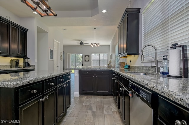 kitchen with sink, hanging light fixtures, stainless steel dishwasher, kitchen peninsula, and light stone countertops