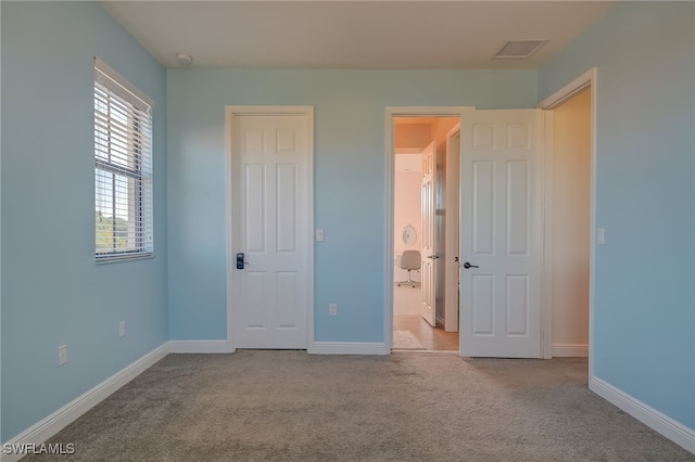 unfurnished bedroom featuring light carpet and connected bathroom