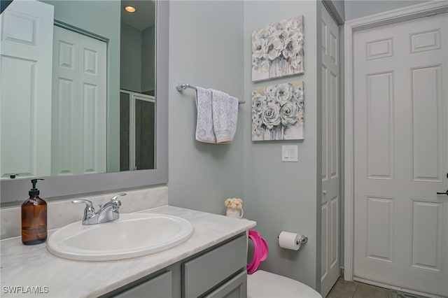 bathroom with vanity, tile patterned flooring, a shower with door, and toilet