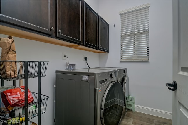 clothes washing area featuring separate washer and dryer, dark wood-type flooring, and cabinets