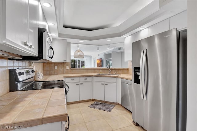 kitchen featuring appliances with stainless steel finishes, sink, white cabinets, backsplash, and a raised ceiling