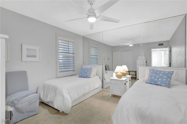 tiled bedroom with ceiling fan and a closet