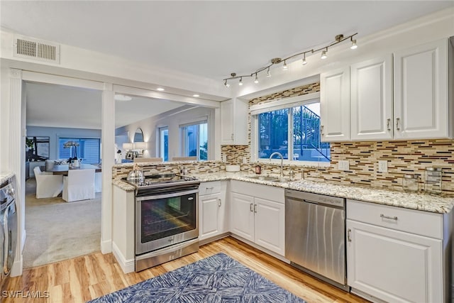 kitchen featuring tasteful backsplash, sink, white cabinets, light hardwood / wood-style floors, and stainless steel appliances