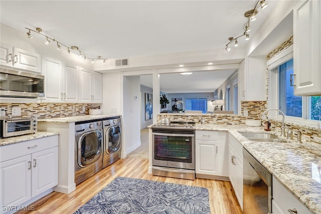 kitchen with backsplash, washer and clothes dryer, white cabinets, and appliances with stainless steel finishes