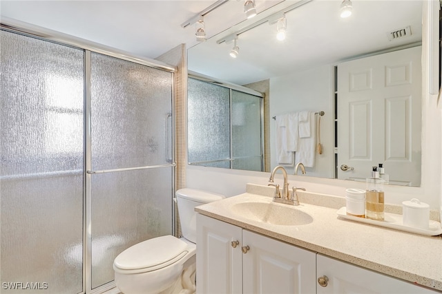 bathroom with a shower with door, vanity, and toilet