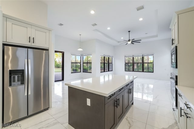 kitchen featuring decorative light fixtures, appliances with stainless steel finishes, a healthy amount of sunlight, and a tray ceiling