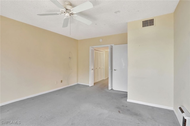 carpeted spare room featuring a textured ceiling and ceiling fan