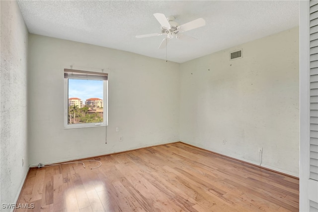 unfurnished room featuring ceiling fan, a textured ceiling, and light wood-type flooring